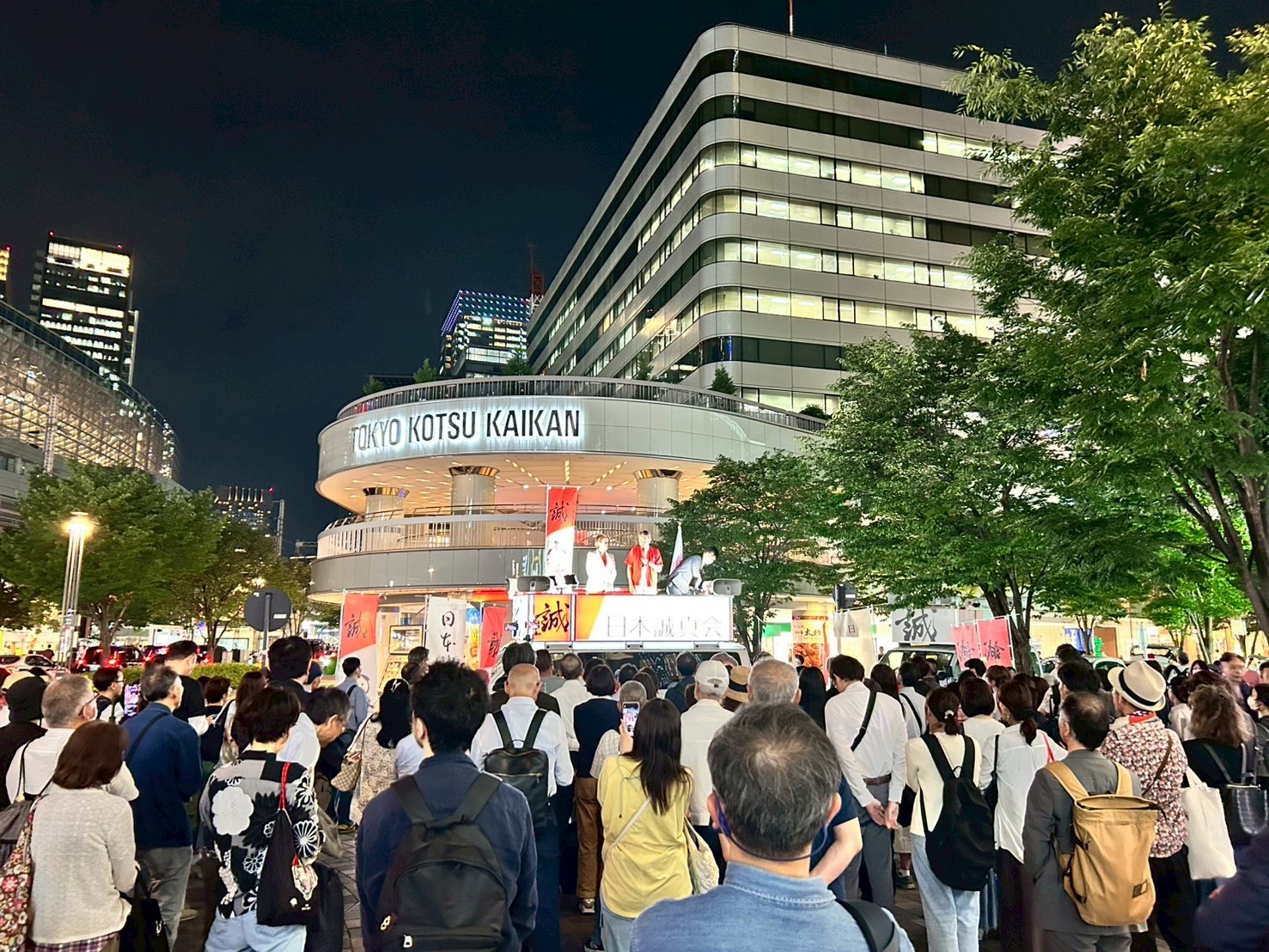 夜の東京交通会館前、日本誠真会の街宣車と集まった大勢の聴衆